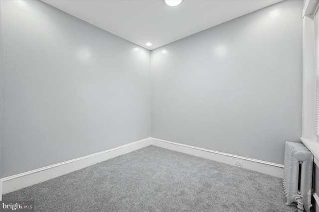 carpeted empty room featuring radiator heating unit