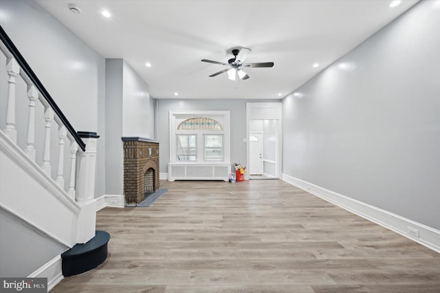 foyer entrance with ceiling fan, radiator, a fireplace, and light hardwood / wood-style floors