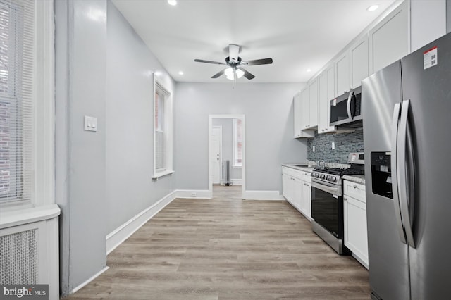 kitchen featuring tasteful backsplash, appliances with stainless steel finishes, ceiling fan, light hardwood / wood-style floors, and white cabinets