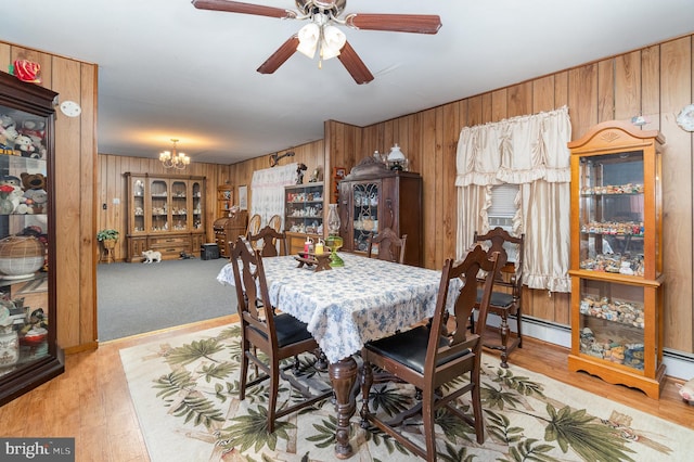 dining area featuring wooden walls, light hardwood / wood-style flooring, and a baseboard heating unit