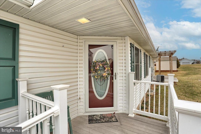 view of exterior entry featuring central AC and a lawn