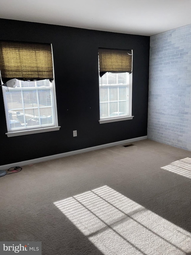 empty room with brick wall and carpet floors