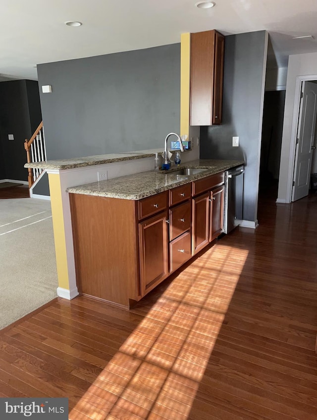 kitchen featuring sink, dark wood-type flooring, dishwasher, light stone counters, and kitchen peninsula