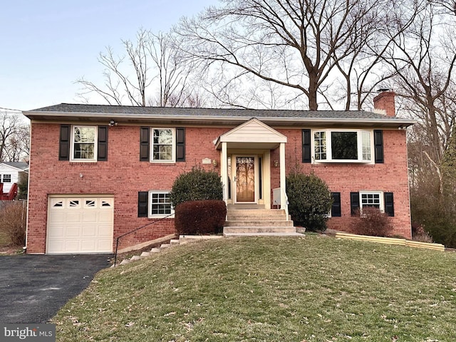 raised ranch featuring a garage and a front lawn