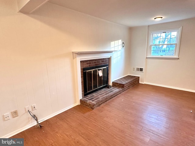 unfurnished living room featuring a brick fireplace and wood-type flooring