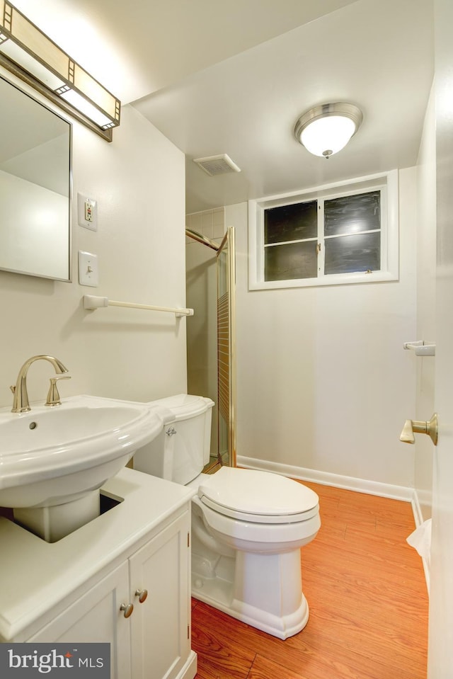 bathroom with toilet, vanity, walk in shower, and wood-type flooring