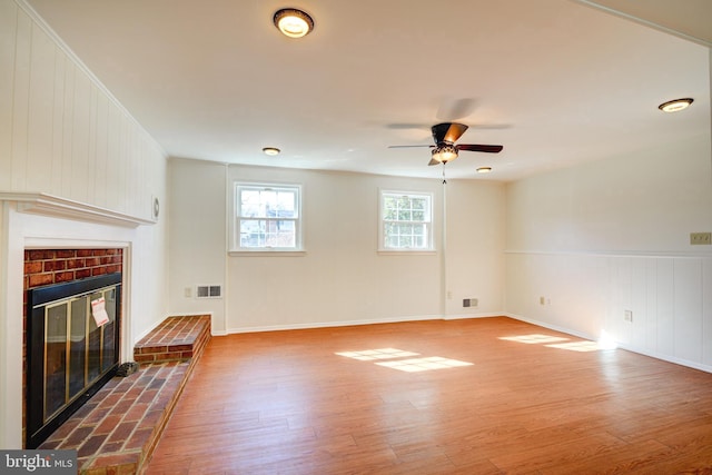 unfurnished living room with a brick fireplace, ceiling fan, and wood-type flooring