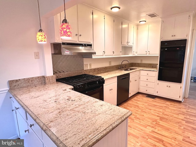 kitchen with sink, light wood-type flooring, white cabinetry, black appliances, and hanging light fixtures