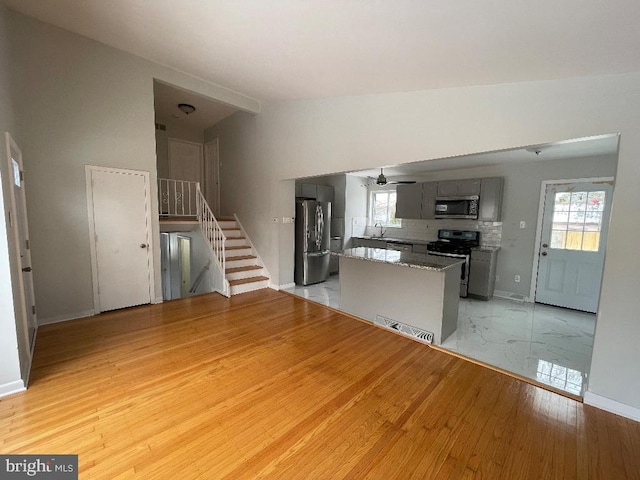 kitchen with lofted ceiling, sink, gray cabinets, stainless steel appliances, and light hardwood / wood-style floors