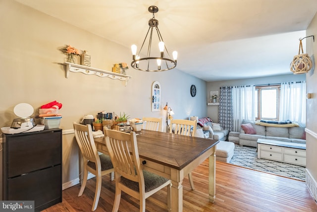 dining space with hardwood / wood-style floors and a chandelier