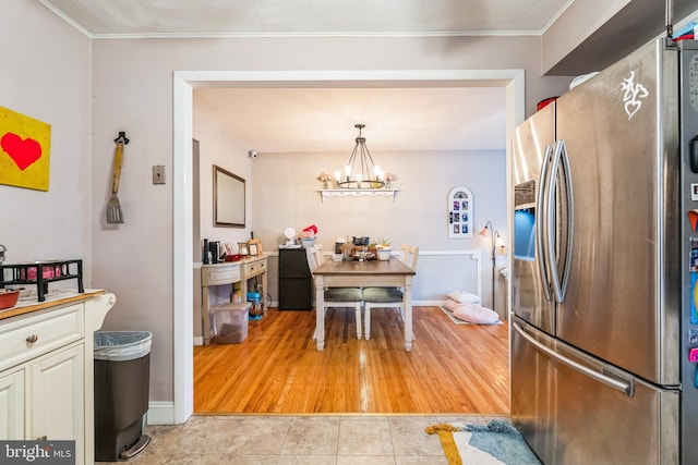 kitchen with light tile patterned flooring, decorative light fixtures, stainless steel fridge, crown molding, and an inviting chandelier