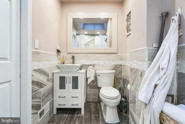 bathroom with vanity, tile walls, and toilet