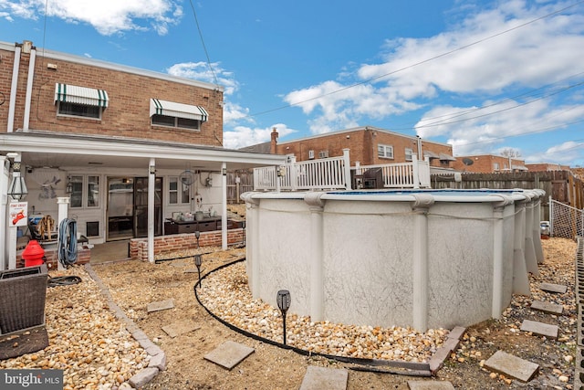 rear view of property with a fenced in pool