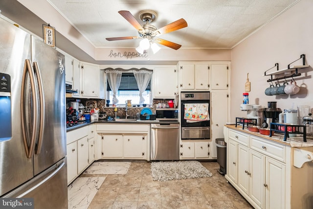 kitchen with sink, ceiling fan, white cabinetry, backsplash, and stainless steel appliances