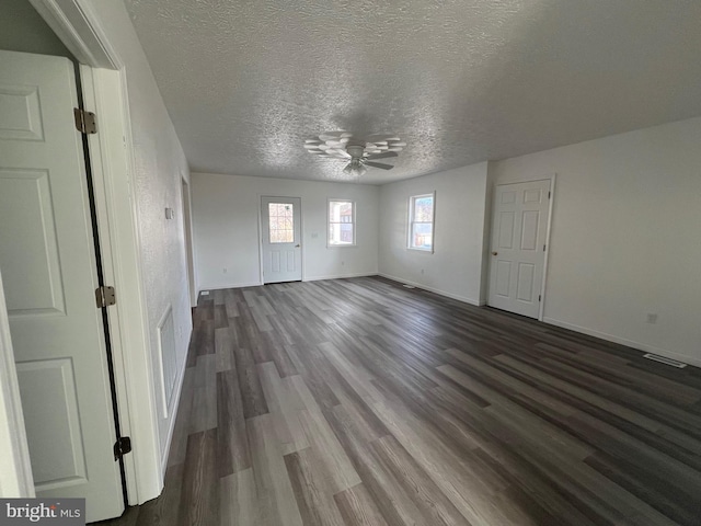 empty room featuring dark wood-type flooring, a textured ceiling, and ceiling fan