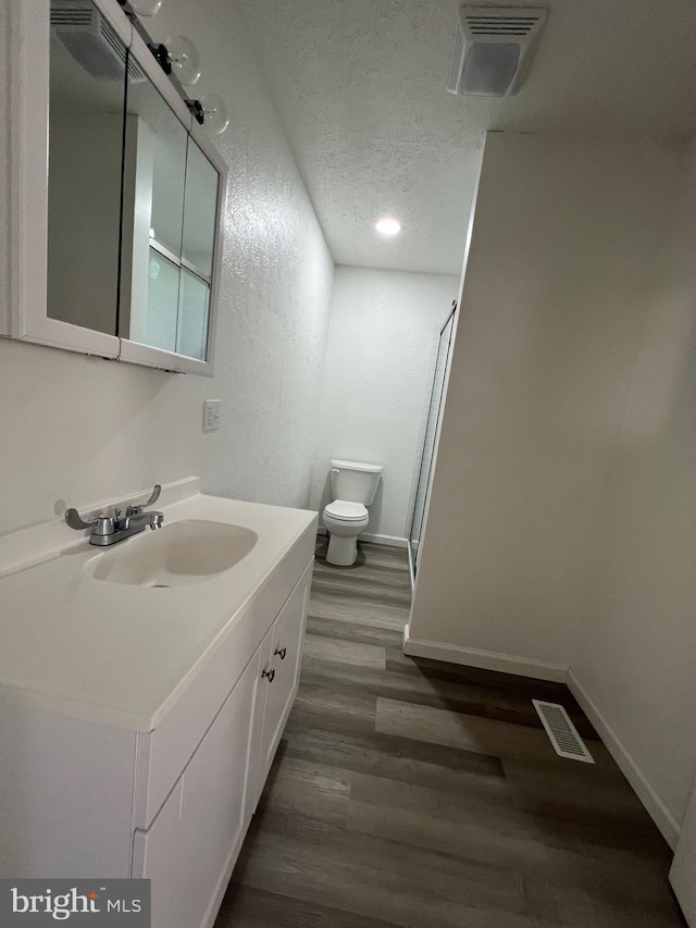 bathroom featuring hardwood / wood-style flooring, vanity, toilet, and a textured ceiling