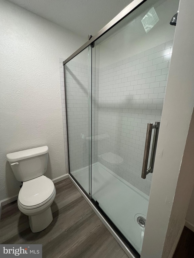 bathroom featuring wood-type flooring, toilet, and an enclosed shower