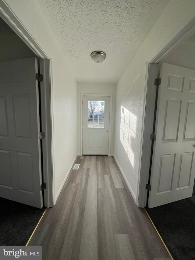 corridor featuring hardwood / wood-style flooring and a textured ceiling