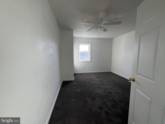 spare room featuring dark colored carpet, ceiling fan, and a textured ceiling