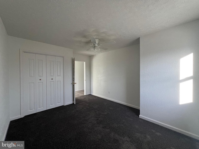 unfurnished bedroom featuring ceiling fan, dark carpet, a closet, and a textured ceiling