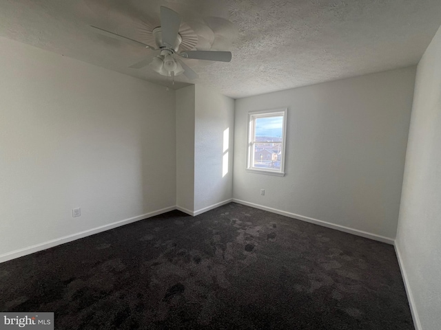 empty room with ceiling fan, a textured ceiling, and dark colored carpet