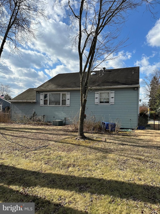 rear view of property featuring a yard and central AC unit