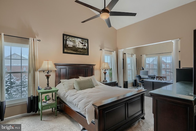 bedroom featuring multiple windows, decorative columns, and light carpet