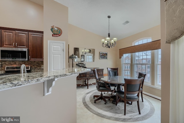 dining room featuring high vaulted ceiling and an inviting chandelier