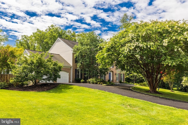 view of property hidden behind natural elements featuring a garage and a front yard