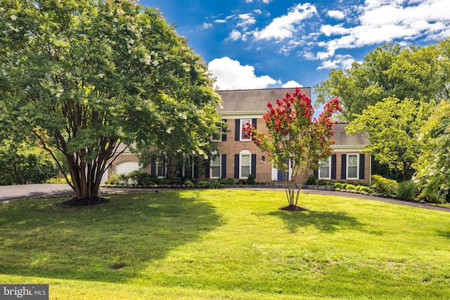 colonial inspired home featuring brick siding and a front lawn