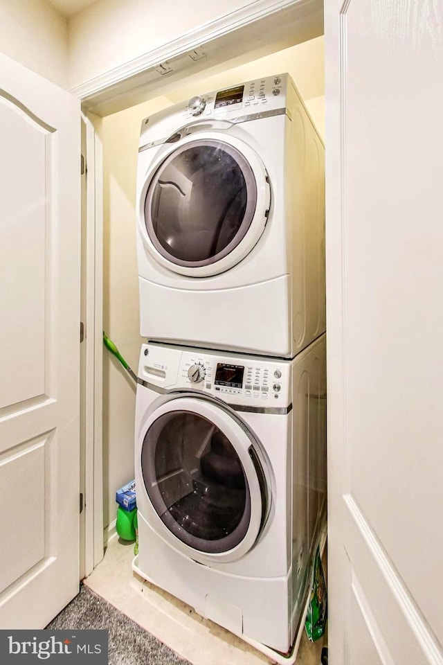 clothes washing area featuring stacked washer and dryer