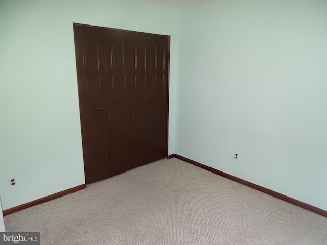 unfurnished bedroom with a closet and light carpet