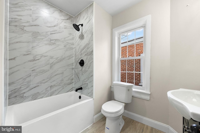 full bathroom featuring tiled shower / bath combo, wood-type flooring, sink, and toilet