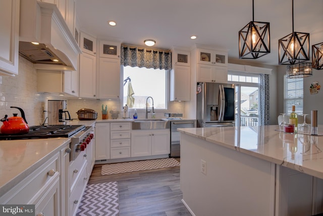 kitchen featuring sink, appliances with stainless steel finishes, white cabinetry, light stone counters, and custom exhaust hood