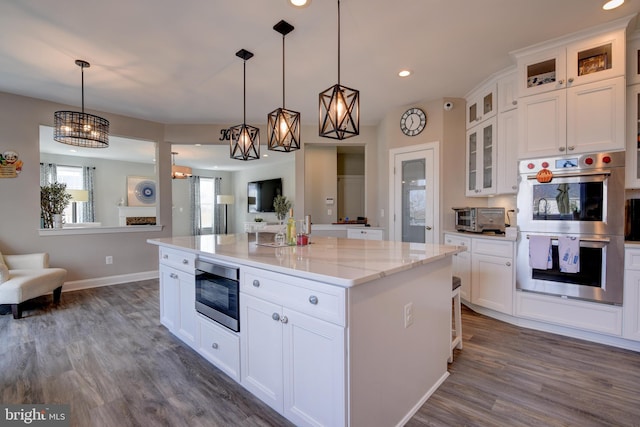 kitchen with built in microwave, white cabinetry, a center island, hanging light fixtures, and double oven