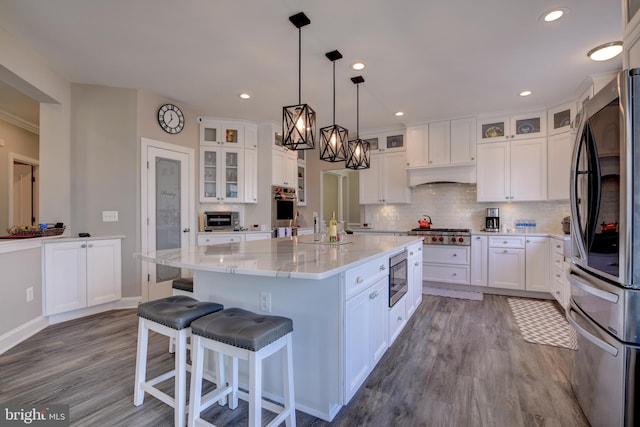 kitchen with white cabinetry, tasteful backsplash, a center island, appliances with stainless steel finishes, and light stone countertops