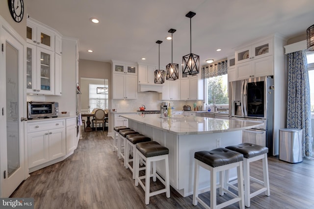 kitchen featuring white cabinetry, pendant lighting, stainless steel refrigerator, and a kitchen island