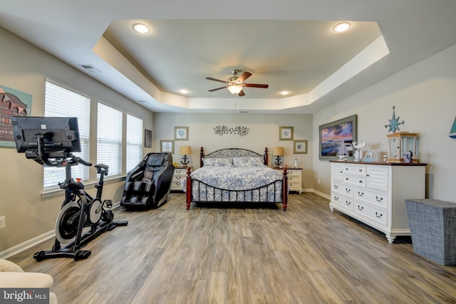 bedroom featuring hardwood / wood-style floors, a raised ceiling, and ceiling fan