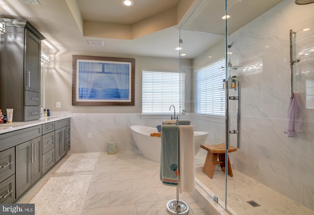 bathroom with vanity, tile walls, and separate shower and tub