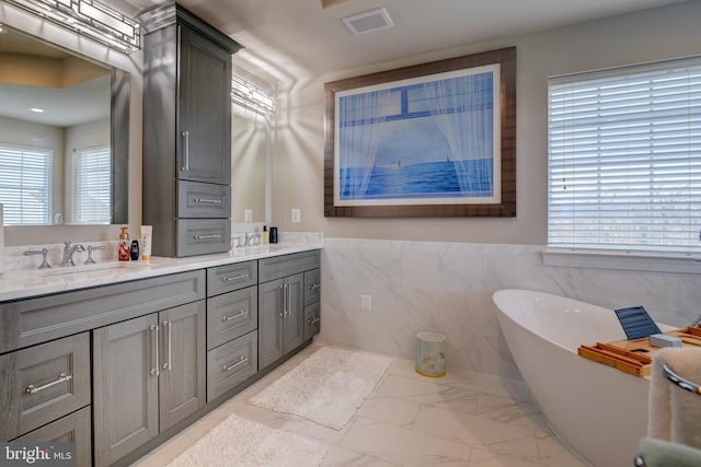 bathroom with vanity, tile walls, and a bathtub