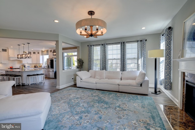 living room featuring an inviting chandelier, dark wood-type flooring, and a high end fireplace