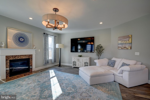 living room with a high end fireplace, dark wood-type flooring, and a chandelier