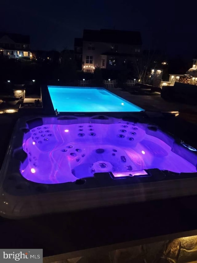 pool at twilight featuring a hot tub