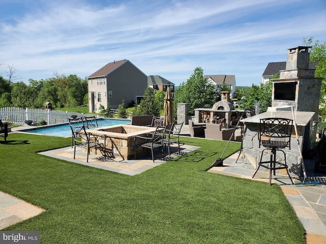 exterior space with a fenced in pool, a patio area, and an outdoor stone fireplace