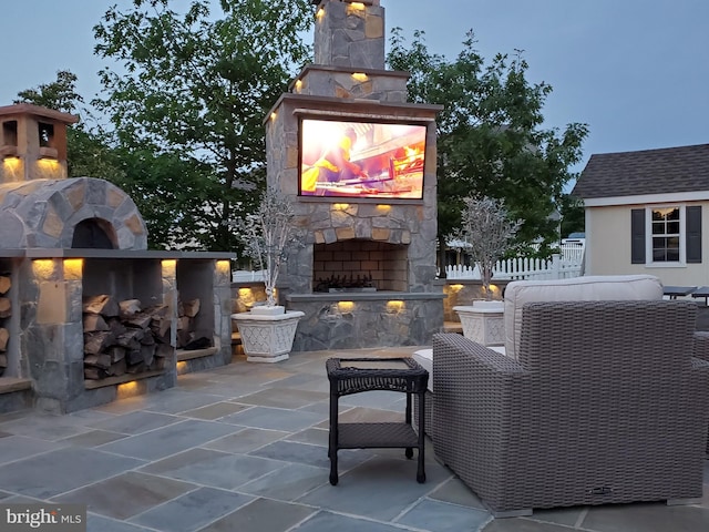 patio terrace at dusk featuring an outdoor stone fireplace