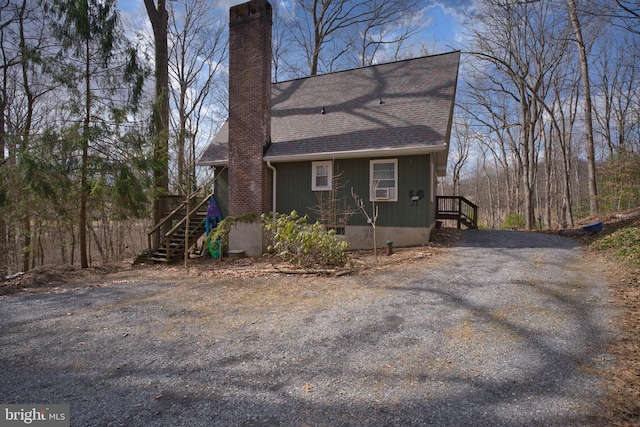 view of front of house featuring a shingled roof, crawl space, driveway, and a chimney