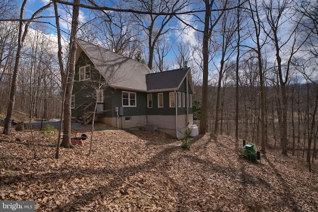 view of home's exterior with a shingled roof and a chimney