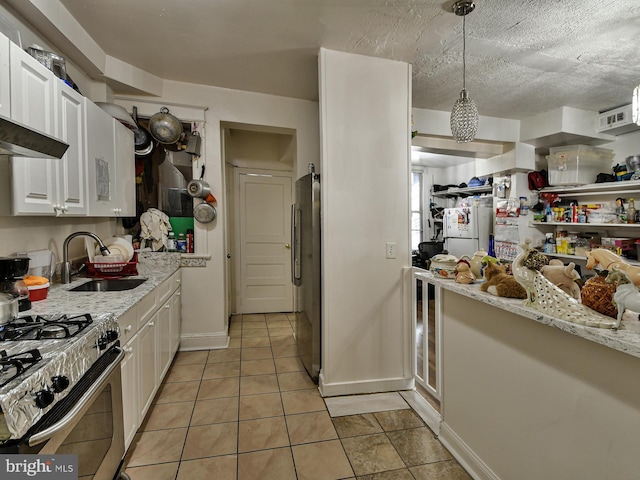 kitchen featuring sink, appliances with stainless steel finishes, light stone counters, white cabinets, and decorative light fixtures