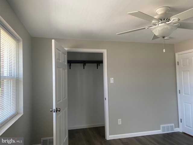 unfurnished bedroom featuring ceiling fan, dark hardwood / wood-style flooring, and a closet