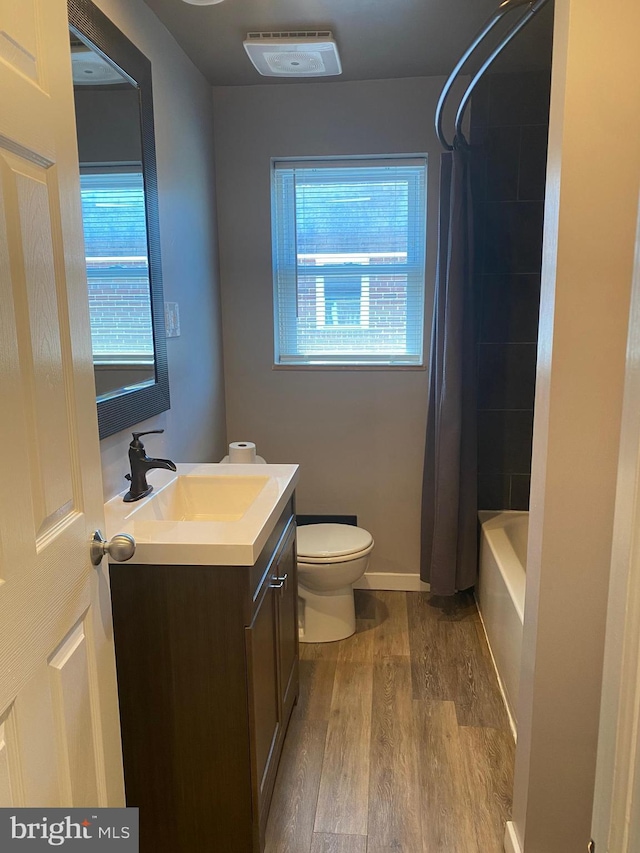 full bathroom featuring shower / bathtub combination with curtain, hardwood / wood-style floors, vanity, and toilet